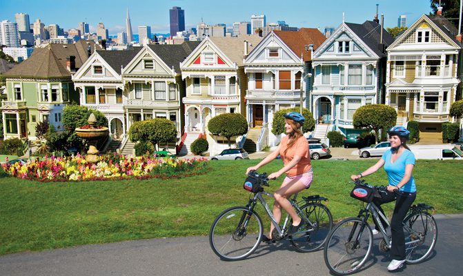 People biking past houses in San Francisco
