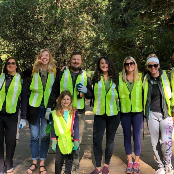 A small group of people in yellow vests posing for a photo during a tour in California.