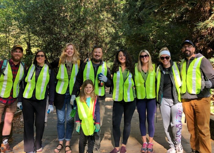 A small group of people in yellow vests posing for a photo during a tour in California.