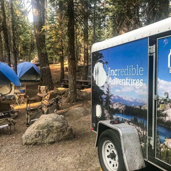 A small group tour trailer parked in the woods near Yosemite National Park, offering guided tours.