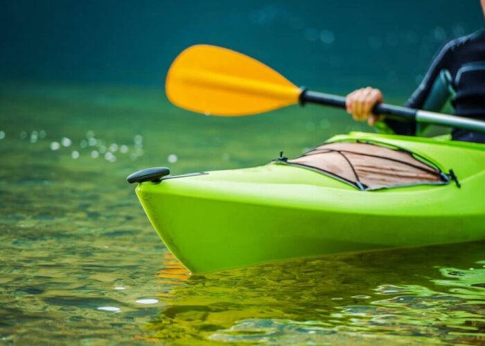 A man is paddling a green kayak in the water near Yosemite National Park.