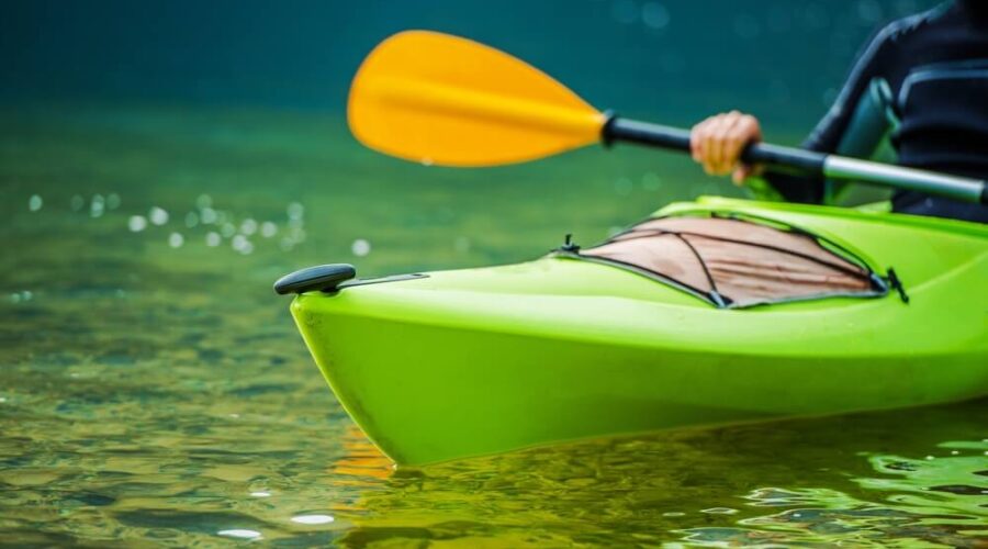 A man is paddling a green kayak in the water near Yosemite National Park.