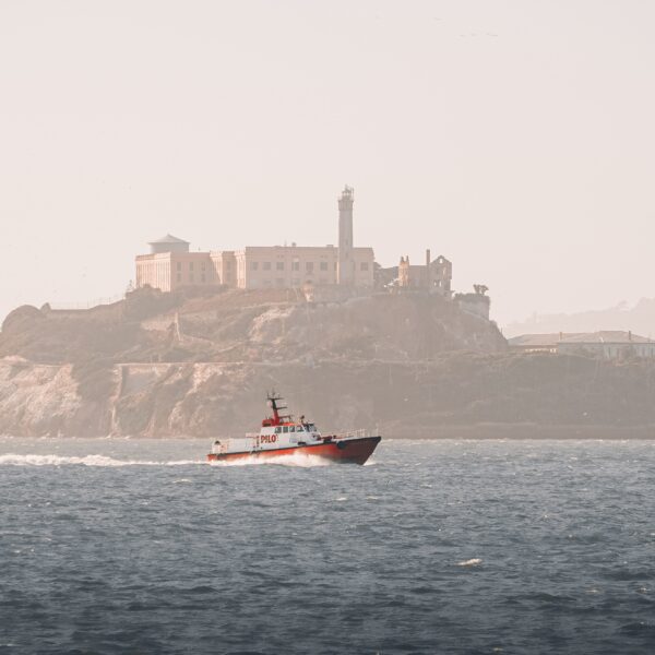 A boat sails near Alcatraz Island on a hazy day, offering tours to Muir Woods and Sausalito.