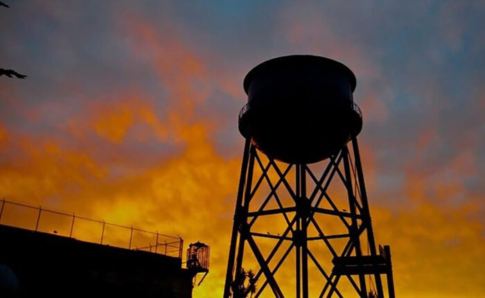 A small group tours California water tower, silhouetted against a colorful sky.