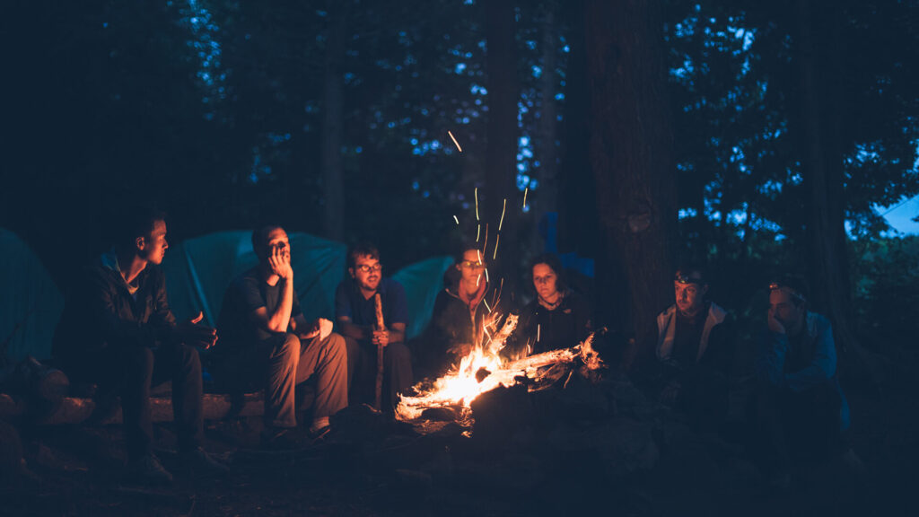 A group of people sitting around a campfire at Yosemite National Park.