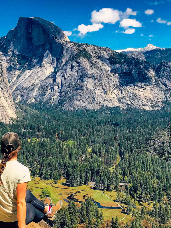 A woman sits on a rock overlooking Yosemite Valley during a small group tour in California.