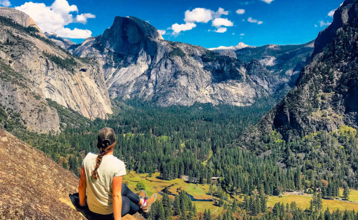A woman sits on a rock overlooking Yosemite Valley during a small group tour in California.