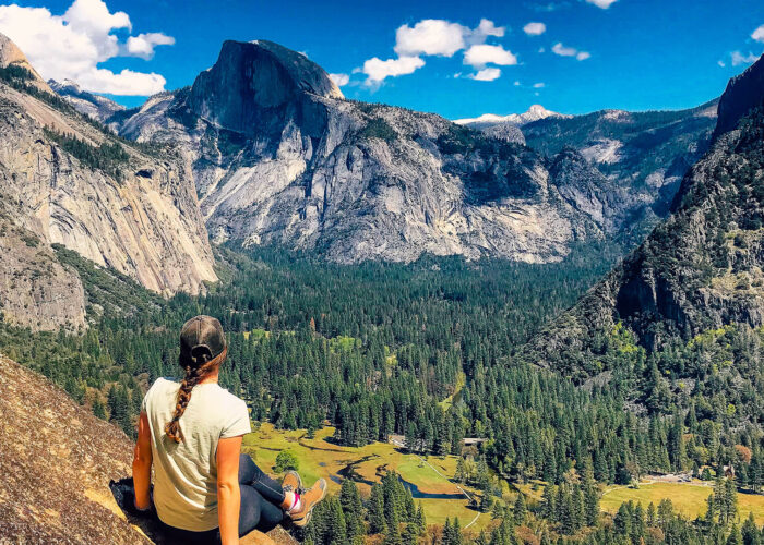 A woman sits on a rock overlooking Yosemite Valley during a small group tour in California.