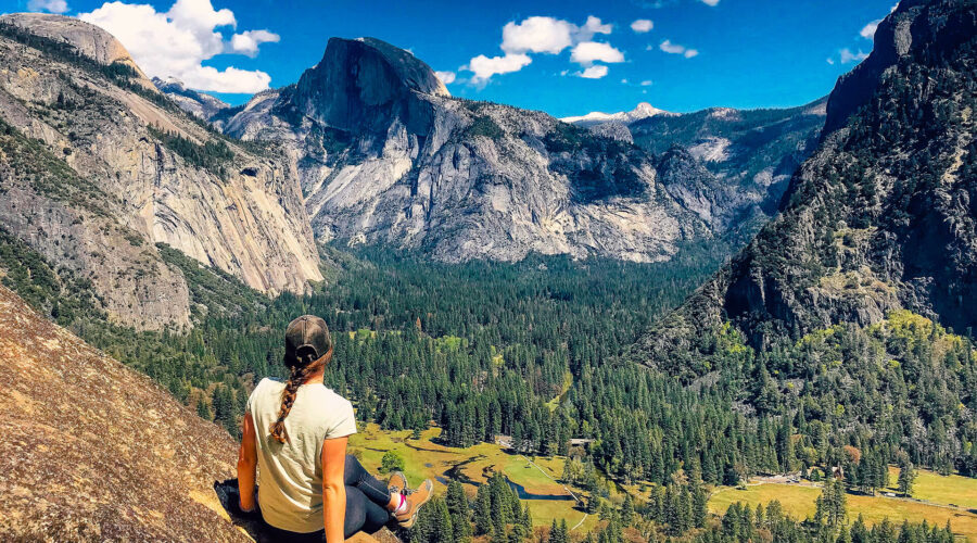 A woman sits on a rock overlooking Yosemite Valley during a small group tour in California.