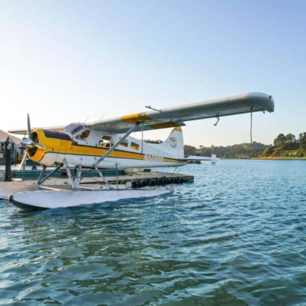 A seaplane tours docked on a calm body of water at sunset in San Francisco.