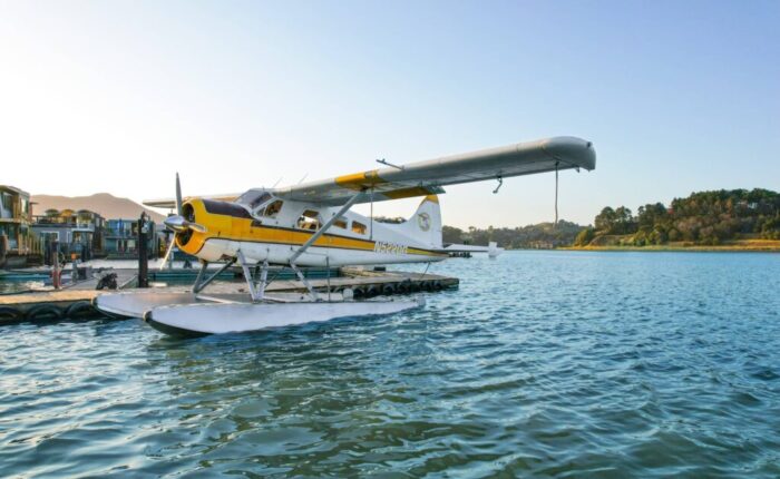 A seaplane tours docked on a calm body of water at sunset in San Francisco.