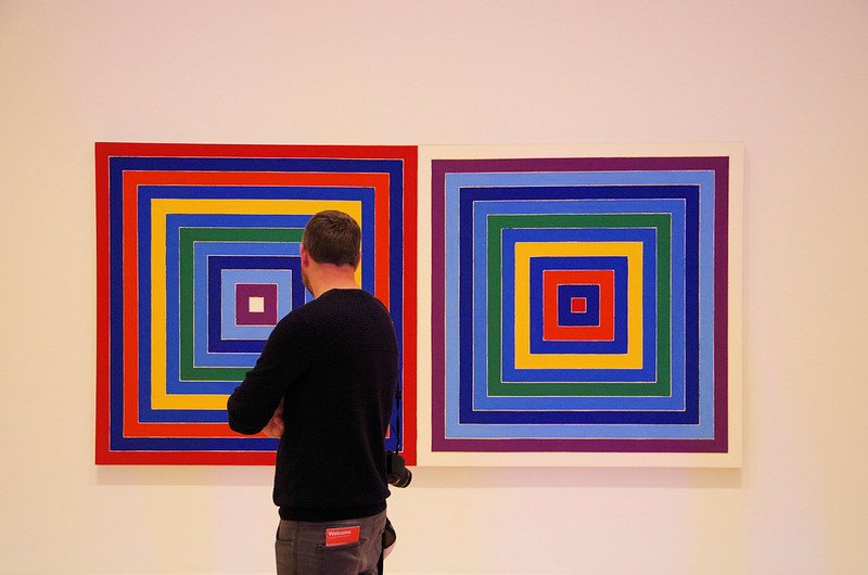 A man admiring two colorful paintings in the best place to see art in San Francisco.