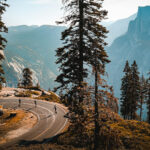 Winding mountain road with cyclists and a view of half dome in Yosemite National Park, offering a good perspective for non-hikers.