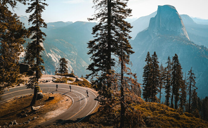 Winding mountain road with cyclists and a view of half dome in Yosemite National Park, offering a good perspective for non-hikers.