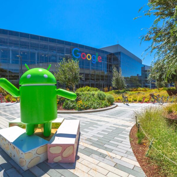 A large Android mascot statue in front of the Google headquarters building on a sunny day during a Silicon Valley tour.