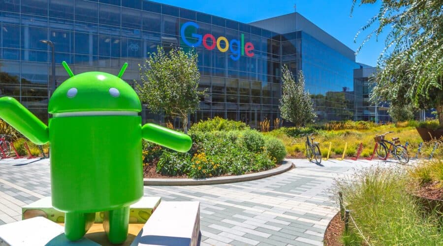 A large Android mascot statue in front of the Google headquarters building on a sunny day during a Silicon Valley tour.