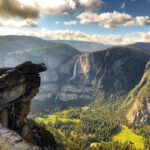 Overlooking Yosemite Valley with a view of lush green meadows, cascading waterfalls, and rugged cliffs under a cloudy sky, this vista is one of the highlights you'll experience on our exclusive 5 Days Tour.