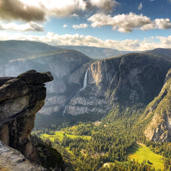 Overlooking Yosemite Valley with a view of lush green meadows, cascading waterfalls, and rugged cliffs under a cloudy sky, this vista is one of the highlights you'll experience on our exclusive 5 Days Tour.