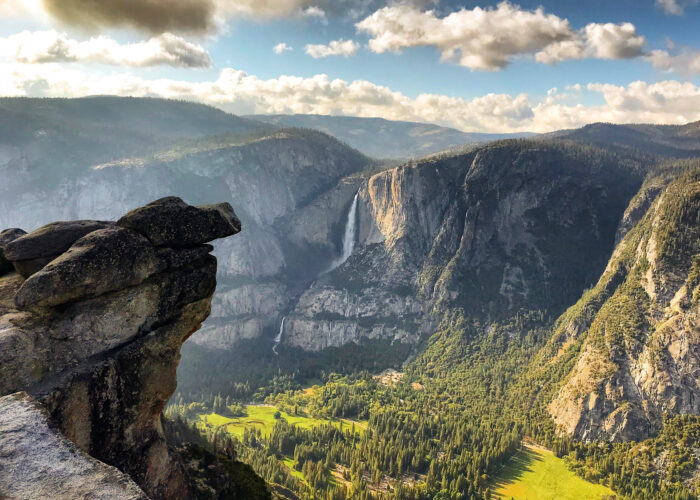 Overlooking Yosemite Valley with a view of lush green meadows, cascading waterfalls, and rugged cliffs under a cloudy sky, this vista is one of the highlights you'll experience on our exclusive 5 Days Tour.