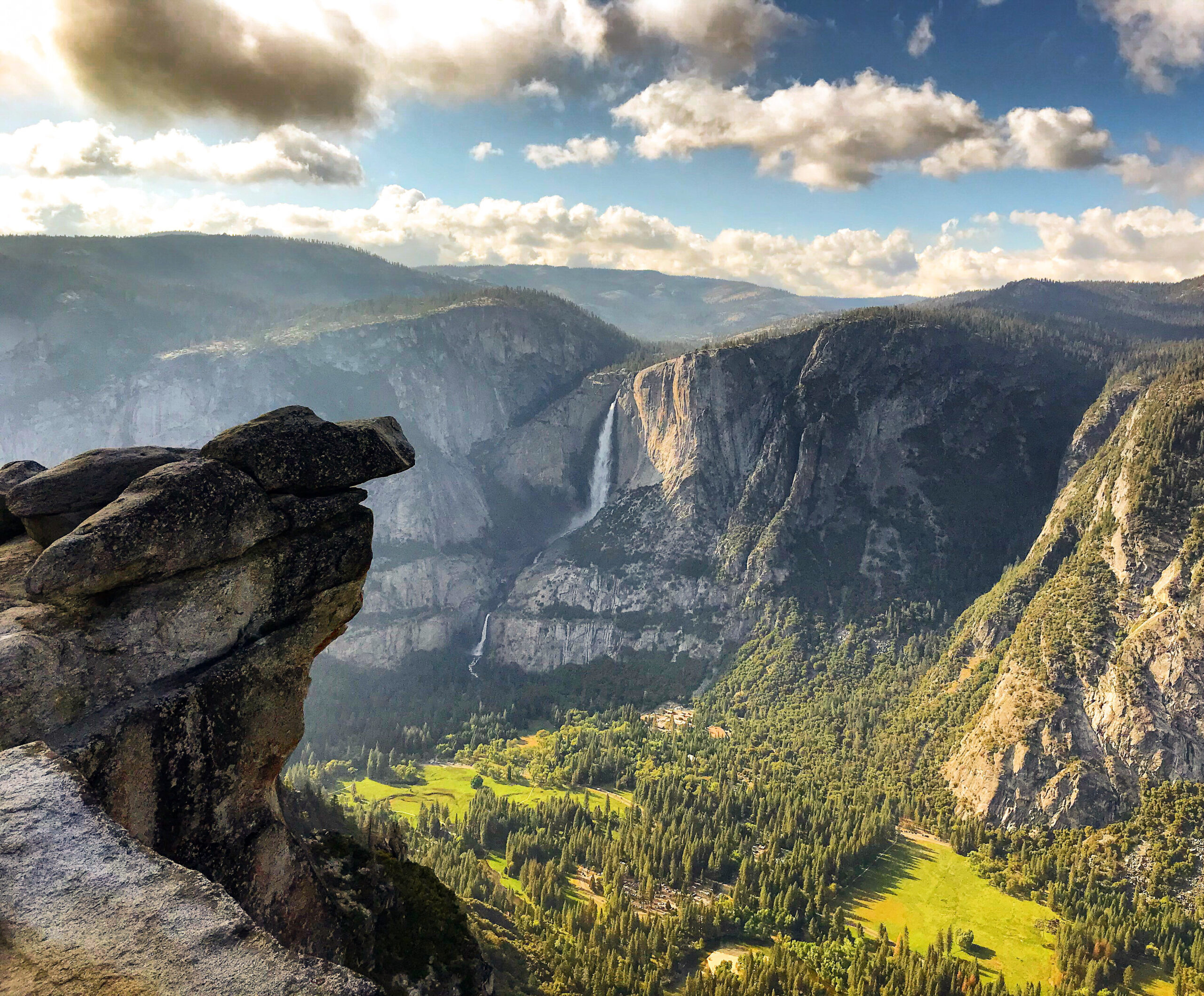 Overlooking Yosemite Valley with a view of lush green meadows, cascading waterfalls, and rugged cliffs under a cloudy sky, this vista is one of the highlights you'll experience on our exclusive 5 Days Tour.