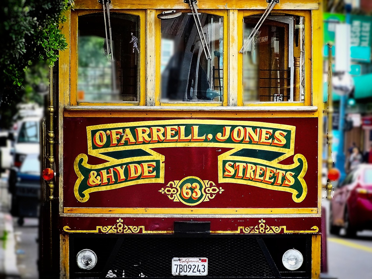 A red and yellow San Francisco cable car with "O'Farrell, Jones & Hyde Streets" and the number 63 displayed on the front—one of the classic kids activities and fun things to do with kids in the city. California license plate visible below.
